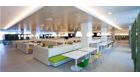 Application picture of CorePro LED PL-C. Recreational area with wooden and white tables, white and coloured modern chairs round luminaires.