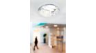 Application picture of CorePro LED PL-C. Zoom on fixture and lamp. Vage background with a person in black walking