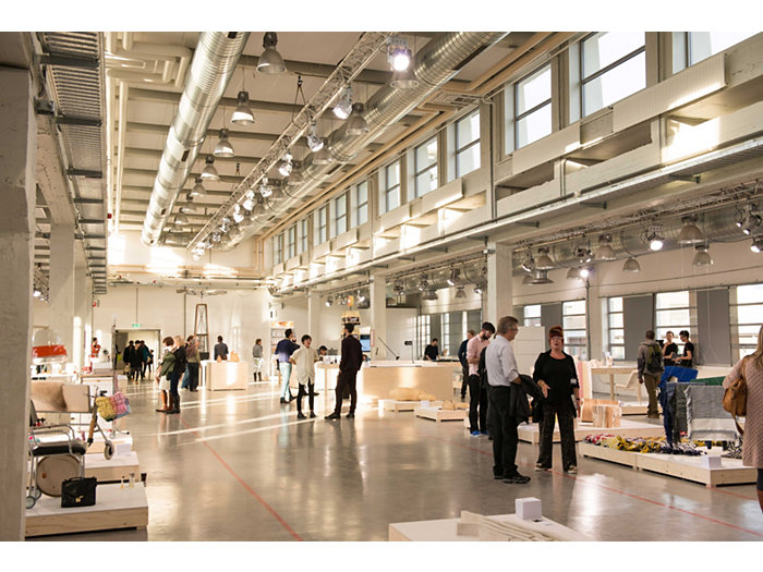 Application picture of MASTERColour CDM MW eco at  an art exhibition, industrial building. Groups of people everywhere looking at the art pieces. Big industrial luminaires