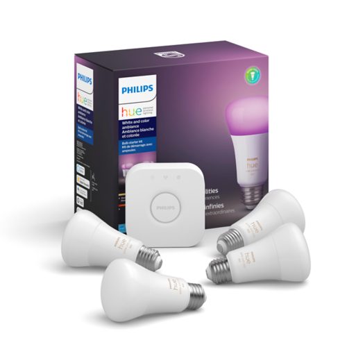 A collection of white smart bulbs and a square hub device placed in front of a box labeled White and color ambiance.