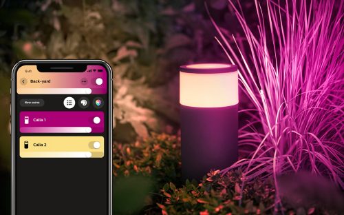 A cylindrical outdoor smart light placed among plants, emitting pink light, with a smartphone app interface for control visible.