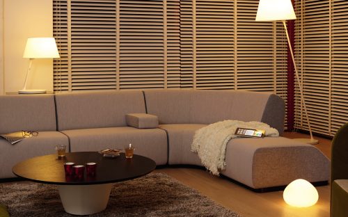 Collection of smart lamps placed on table, floor, and beside a sofa, illuminating a living room with adjustable white light.