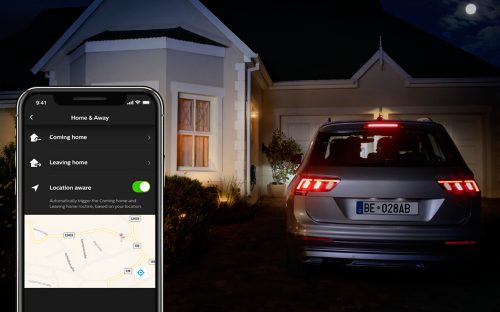 Smartphone displaying Home & Away app interface with Coming home, Leaving home, and Location aware options beside a parked car at night.
