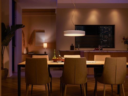 A round ceiling pendant light is suspended above a dining table, casting direct illumination onto the tabletop below.