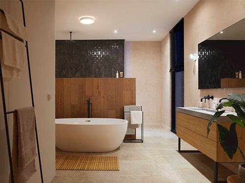 Ceiling-mounted round smart light fixture illuminates a modern bathroom with a freestanding tub and wood accents.