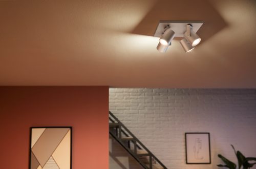 Ceiling-mounted aluminum plate with multiple adjustable cylindrical spotlights illuminating the room below.