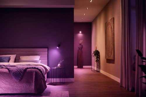 Bedroom and hallway illuminated by adjustable smart spotlights, creating a soft ambient glow with purple and warm tones.