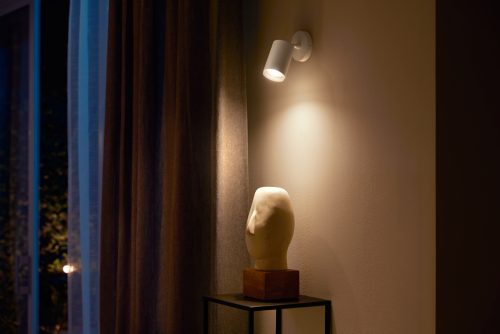 White Fugato single spot light mounted on wall, illuminating a sculpture placed on a stand beneath the fixture.