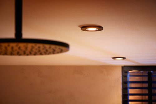 Black recessed ceiling light fixture installed on a light-colored ceiling, emitting downward illumination onto the room below.