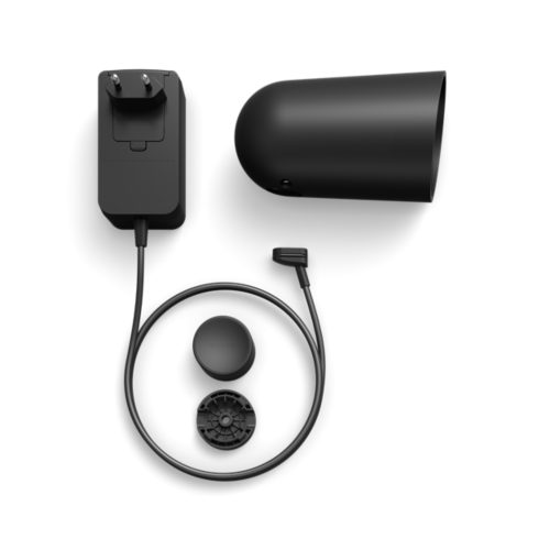 A black smart security camera housing, power adapter with cable, mounting base, and circular accessory are displayed on a white background.
