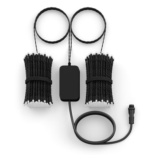 Hand holding a white remote control and pressing a button, likely to adjust smart lighting in a living room setting.