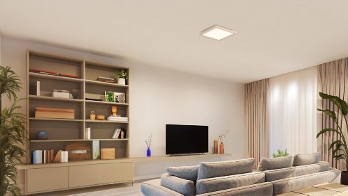 Square ceiling panel light installed centrally in a living room, emitting even white light over seating and shelving areas.