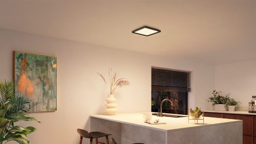 Square black ceiling panel light mounted above a kitchen island, illuminating the countertop and surrounding area with white light.