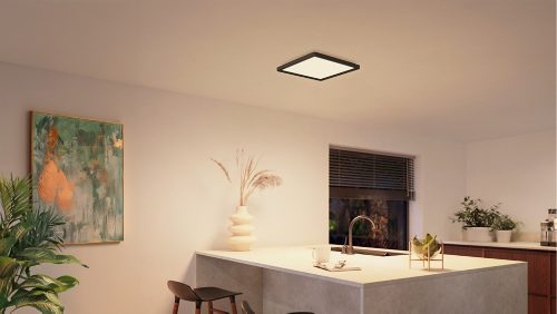 Square black ceiling panel light mounted above a kitchen island, illuminating the countertop and surrounding area with neutral light.