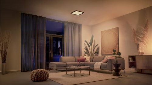 Modern living room with a ceiling panel light casting a soft ambient glow over a neutral sofa, coffee table, and minimalist decor.