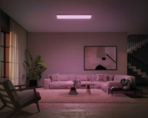 Rectangular ceiling panel light mounted above a living room seating area, casting soft colored illumination onto the space below.