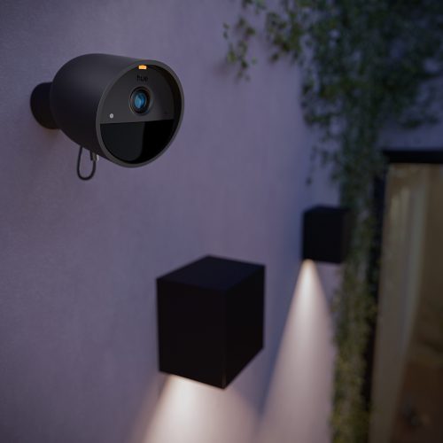 Black outdoor security camera mounted on exterior wall near cube-shaped wall lights, lens facing outward for area monitoring.