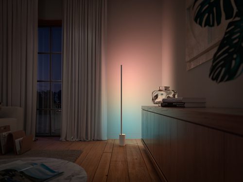 Vertical floor lamp positioned beside cabinet, projecting gradient blue and pink light onto adjacent wall and wooden surface.